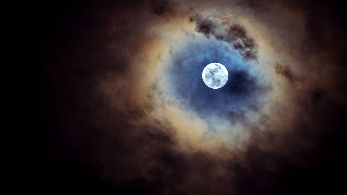 Ein strahlender Vollmond, umgeben von dunklen Wolken und mystischer Atmosphäre.