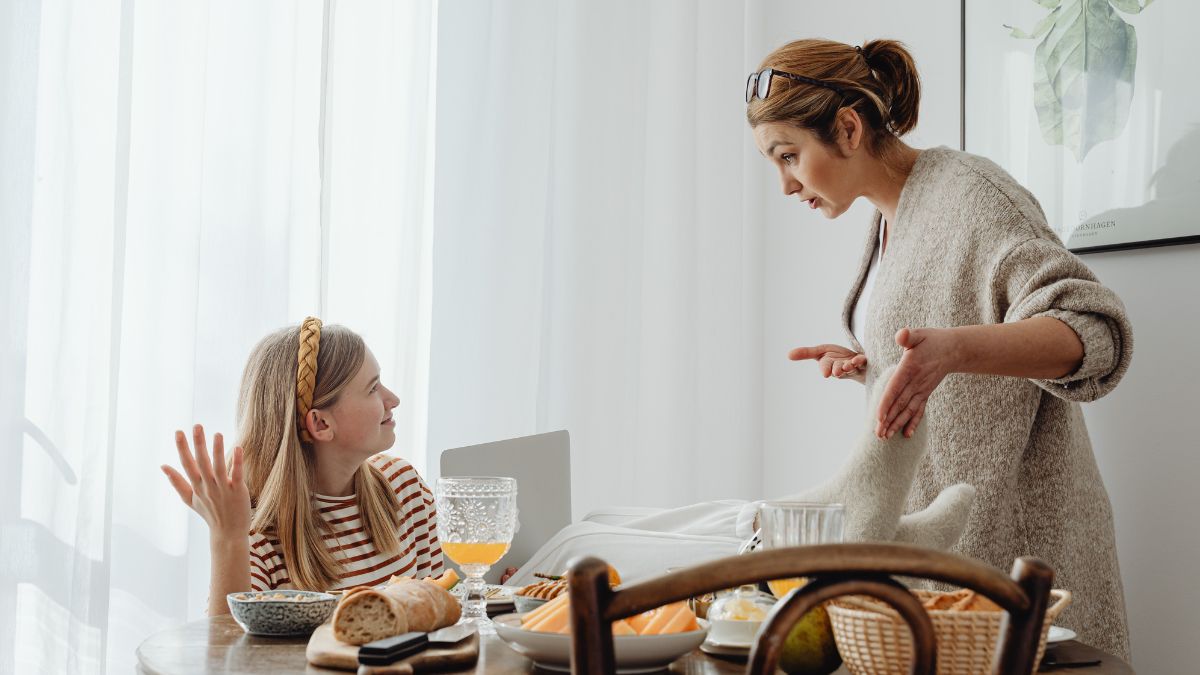 Eine Mutter spricht mit ihrer Tochter am Frühstückstisch über Selbstständigkeit.