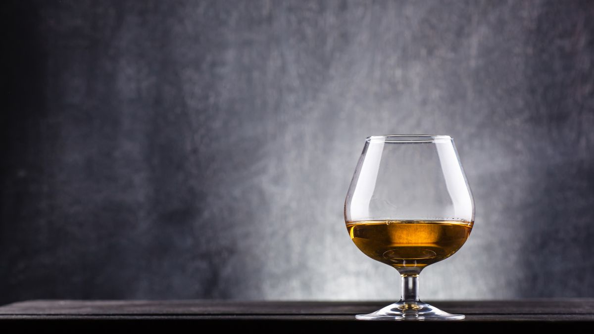 Ein elegantes Glas mit Walnuss-Schnaps auf einem dunklen Tisch.