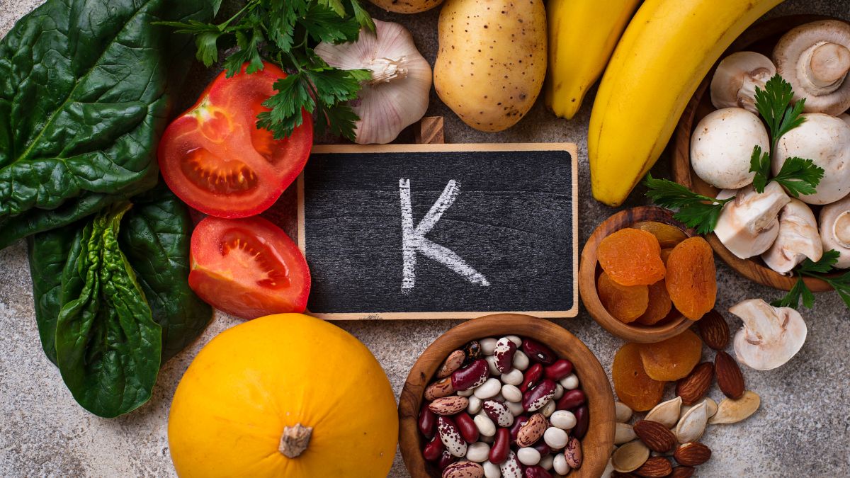 Eine Auswahl an kaliumreichen Lebensmitteln wie Bananen, Spinat und Tomaten.