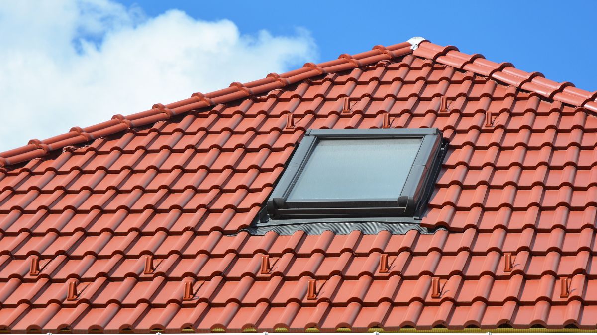 Ein Dachfenster auf einem roten Ziegeldach, das Tageslicht in den Raum lässt.