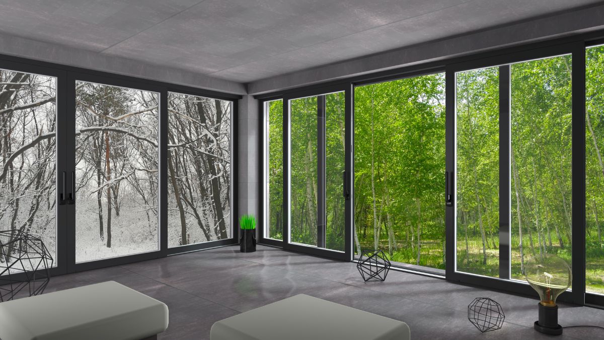 Moderne Schiebetüren trennen einen hellen Raum von einer verschneiten Landschaft und einem grünen Wald.