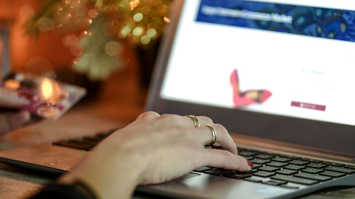 Eine Hand tippt auf einer Laptop-Tastatur, während eine Kreditkarte gehalten wird.