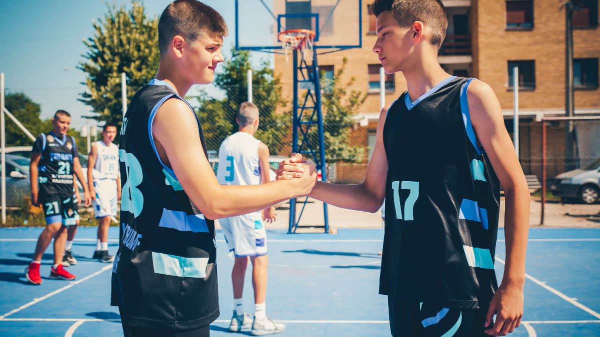 Zwei Jugendliche schütteln sich auf dem Basketballplatz die Hände.