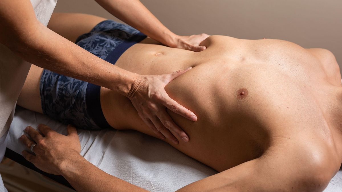Eine Person erhält eine Massage im Bauchbereich zur Förderung der Atmung.